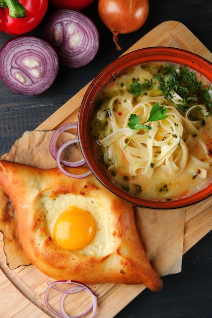 Кавказский суп с лапшой. лагман и хачапури на деревянном столе сверху.