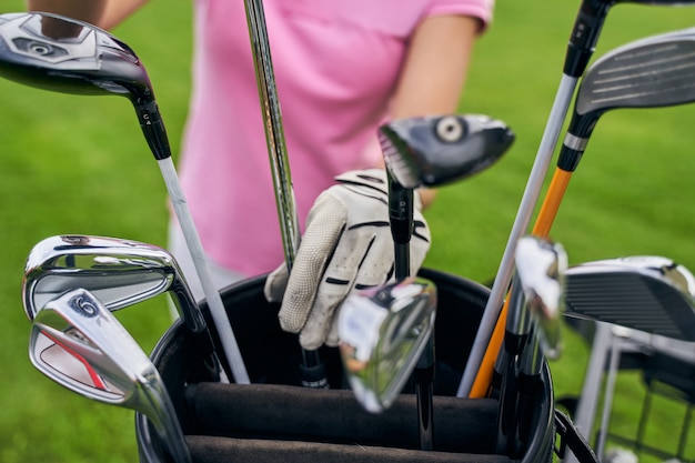 a Caucasian sportswoman reaching for an iron club in a leather bag