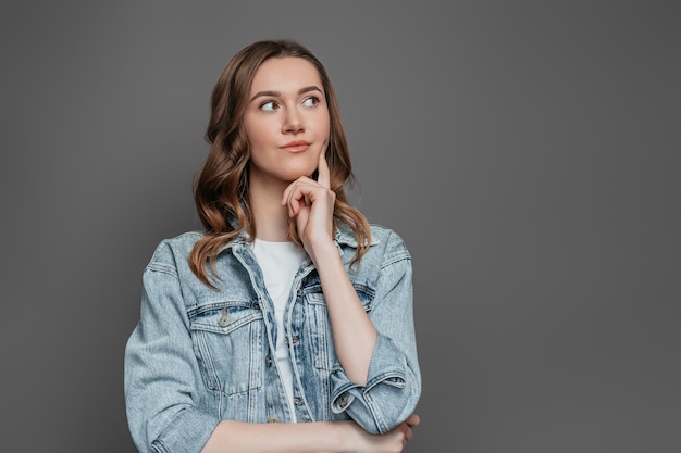 Caucasian student girl thinking and looking away isolated on dark grey wall . concept idea. copy space