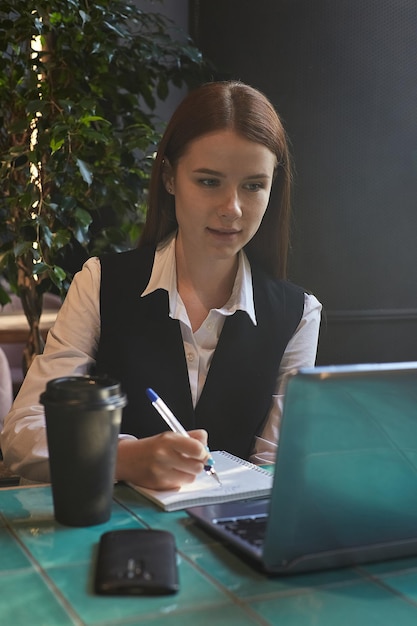 Caucasian student sitting at table of cafe studying with laptop doing homework