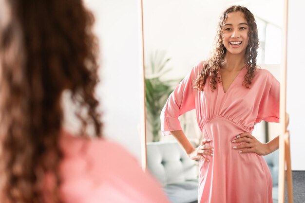 Foto ragazza teenager caucasica che prova un elegante abito rosa a casa