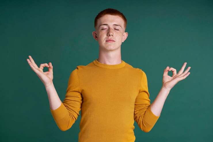 Photo caucasian teenage boy meditating with eyes closed on green background