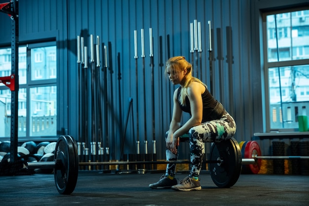 Premium Photo  Caucasian teenage girl practicing in weightlifting in gym.  female sportive model preapring for training with barbell, looks  concentrated. body building, healthy lifestyle, movement and action concept.