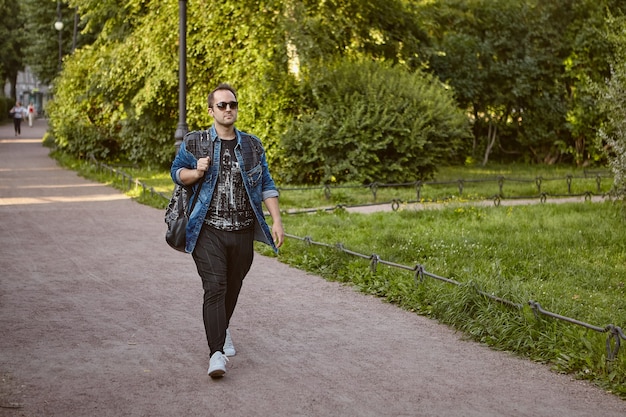 Foto turista caucasico in occhiali da sole e con zaino passeggiate all'aperto.