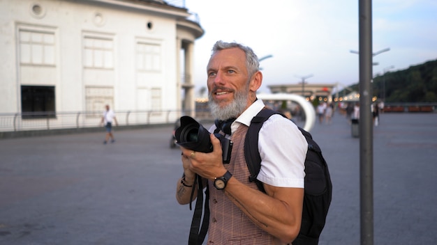 그의 손에 카메라와 함께 백인 여행자 미소.