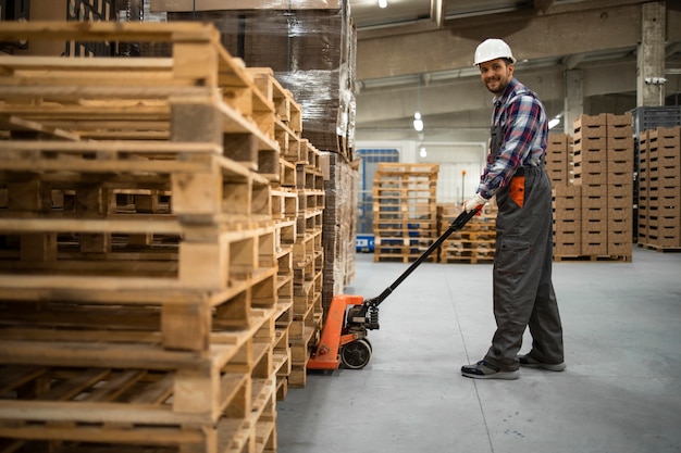 Caucasian warehouse worker lifting weight with manual pallet jack