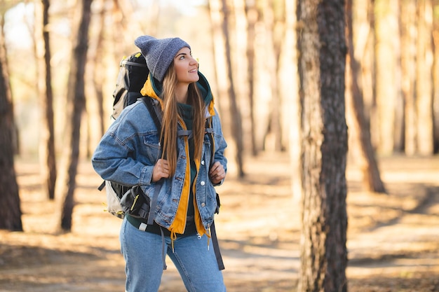 Caucasian white girl with a large hiking backpack in the forest Autumn colors