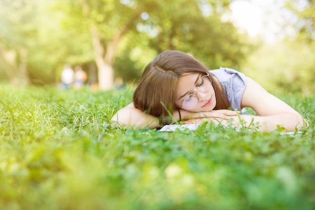 Donna caucasica addormentata mentre legge un libro sul prato verde estivo summer