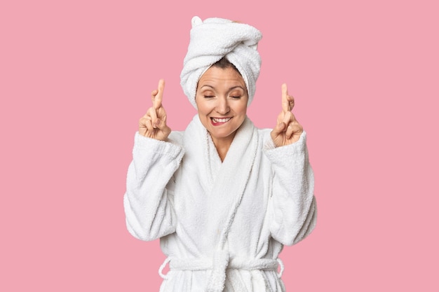 Caucasian woman in bathrobe and towel crossing fingers for having luck