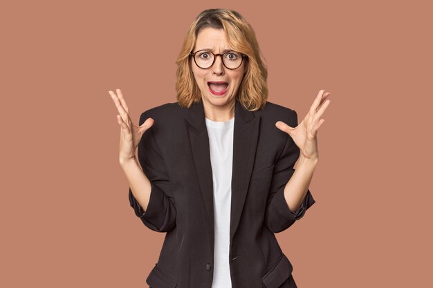 Caucasian woman in black business suit screaming to the sky looking up frustrated