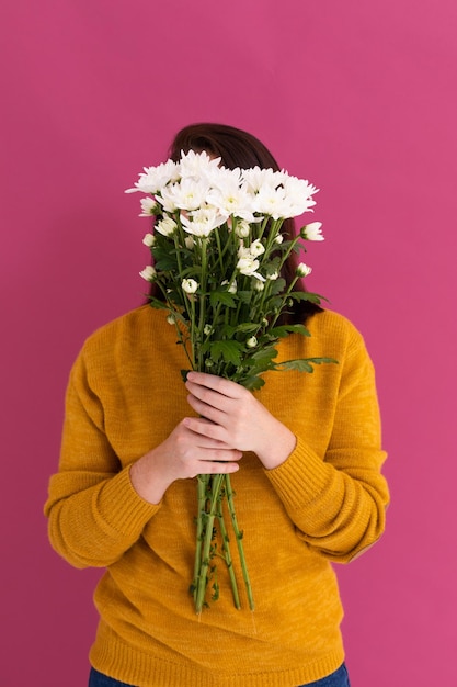 ピンク地に白い花の花束で顔を覆う白人女性。自然の夏の色の花の美しさ。