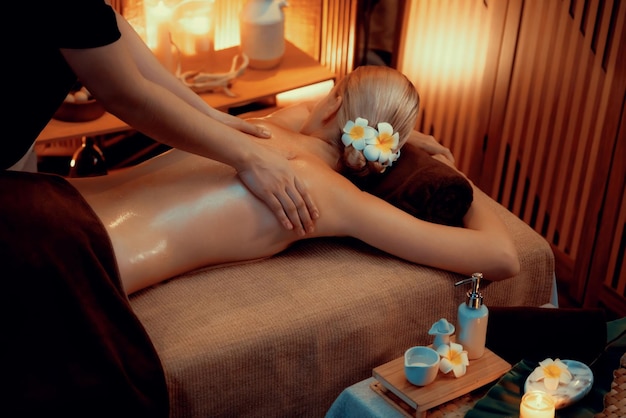 Caucasian woman customer enjoying relaxing antistress spa massage and pampering with beauty skin recreation leisure in warm candle lighting ambient salon spa at luxury resort or hotel Quiescent