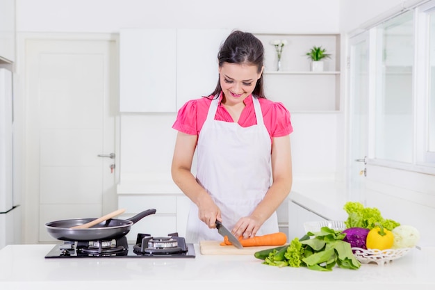 Caucasian woman cut a carrot while preparing foods