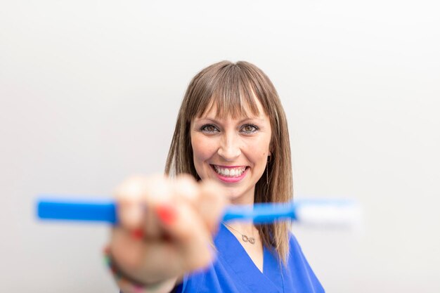 Caucasian woman dentist smiling while showing a toothbrush at the dental clinic