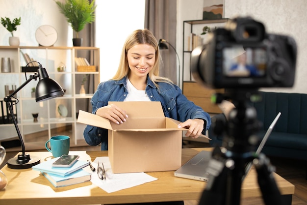 Photo caucasian woman doing live stream while unpacking parcel