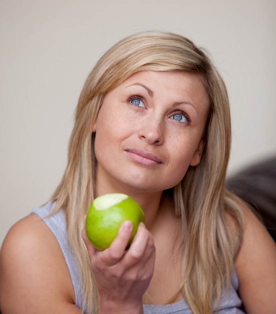 Caucasian woman eating an apple on a sofa 