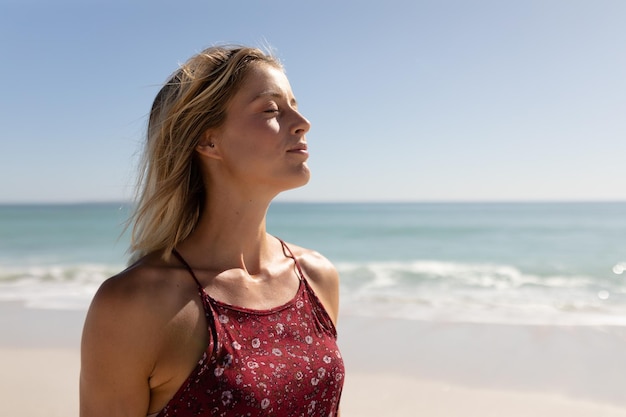 Caucasian woman enjoying her time at the beach with her friends on a sunny day, with her eyes closed