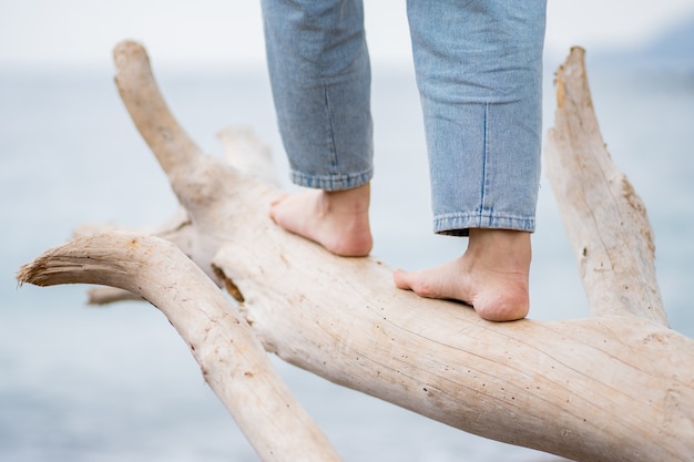 Photo caucasian woman feet walking on white wooden log on beach with sea