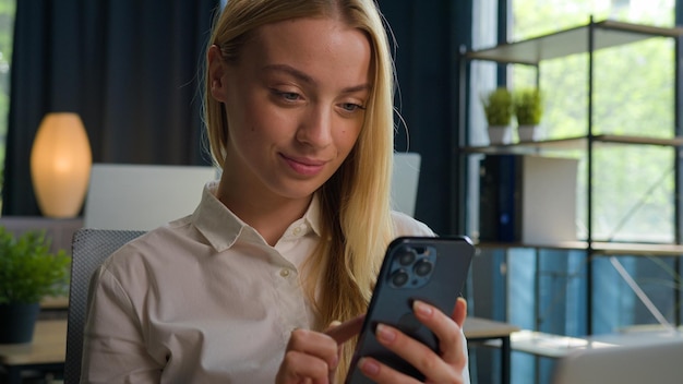 Caucasian woman girl student scrolling mobile phone apps in office smiling businesswoman executive