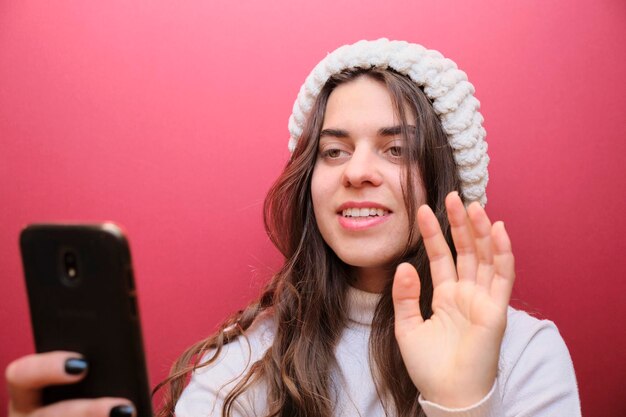 Photo caucasian woman happy to greet by video call her family in the distance on red background