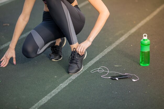 Caucasian woman having ankle injury in running track.\
healthcare and sport concept. green sports bottle for drinking.\
close up.