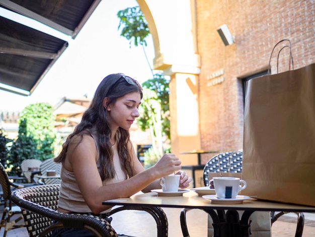 Caucasian woman having a coffee in the street sitting in a cafe after shopping relaxing and resting