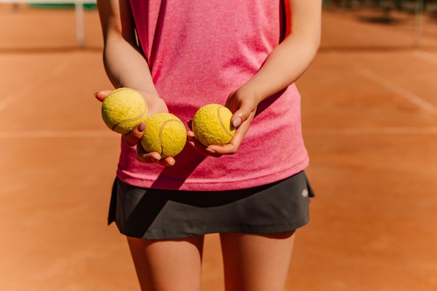 백인 여성은 주말에 클레이 코트 표면에서 테니스 경기를 하는 노란색 녹색 공을 들고 있습니다.