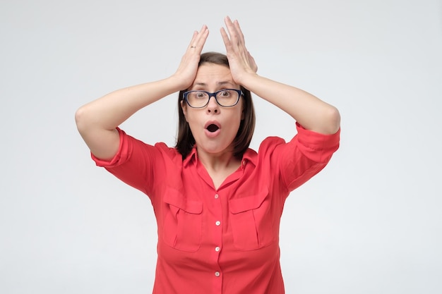 Caucasian woman holding arms on her head being shocked