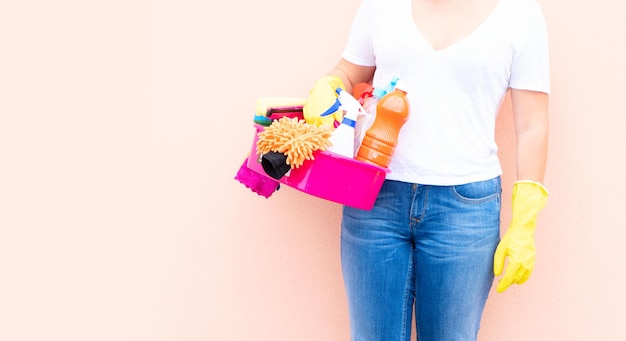 Caucasian woman holding basin with cleaning supplies