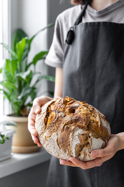 Donna caucasica che tiene il pane fresco dal forno che cuoce il pane fatto in casa