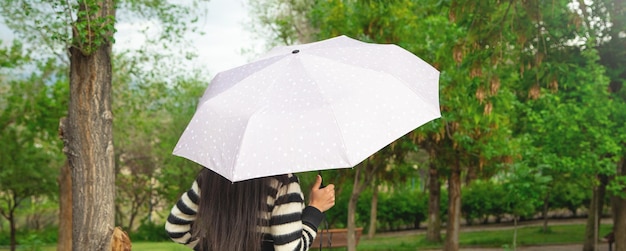 Caucasian woman holding umbrella in park