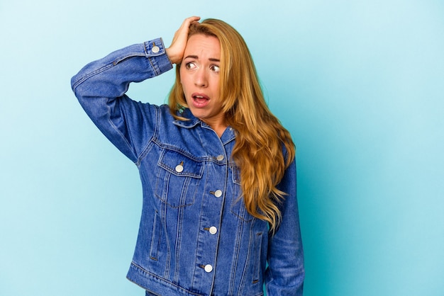 Caucasian woman isolated on blue background being shocked, she has remembered important meeting.