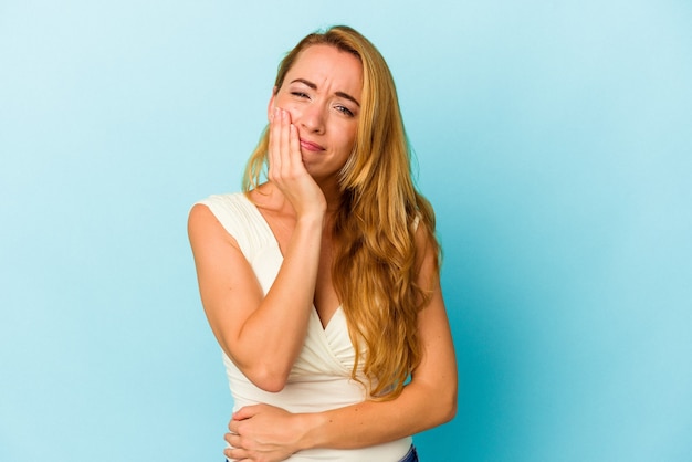 Caucasian woman isolated on blue background blows cheeks, has tired expression. Facial expression concept.