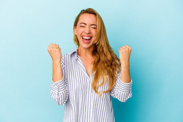 のんびりと興奮して応援して青い背景に分離された白人女性。勝利の概念。