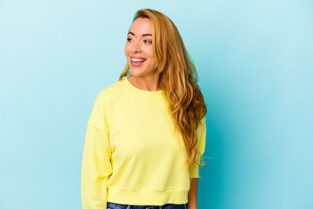 Caucasian woman isolated on blue background laughs and closes eyes, feels relaxed and happy.