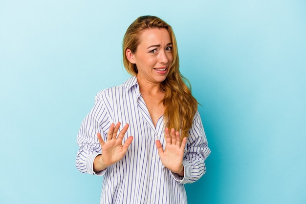 Caucasian woman isolated on blue background rejecting someone showing a gesture of disgust.