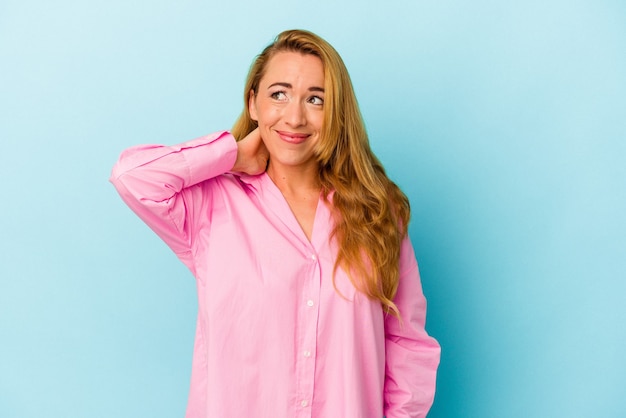 Caucasian woman isolated on blue background touching back of head, thinking and making a choice.