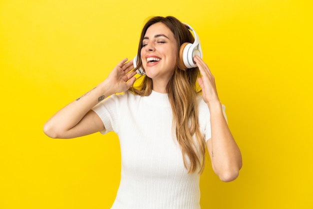 Donna caucasica isolata su sfondo giallo che ascolta musica e canta