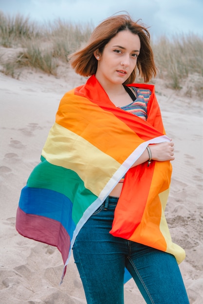 Кавказская женщина-лесбиянка на пляже с радужным флагом гордости - Изображение