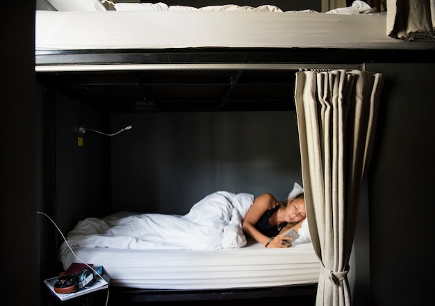 Кавказская женщина, лежа на кровати, с помощью мобильного телефона