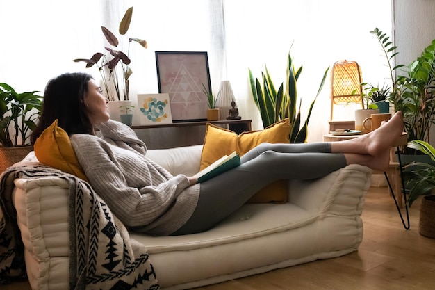 Фото Кавказская женщина, лежа на диване, расслабляющий, читая книгу дома. концепция образа жизни.