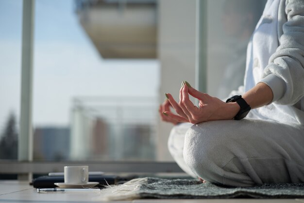 Photo caucasian woman meditates in pajamas sitting in lotus position on plaid before work