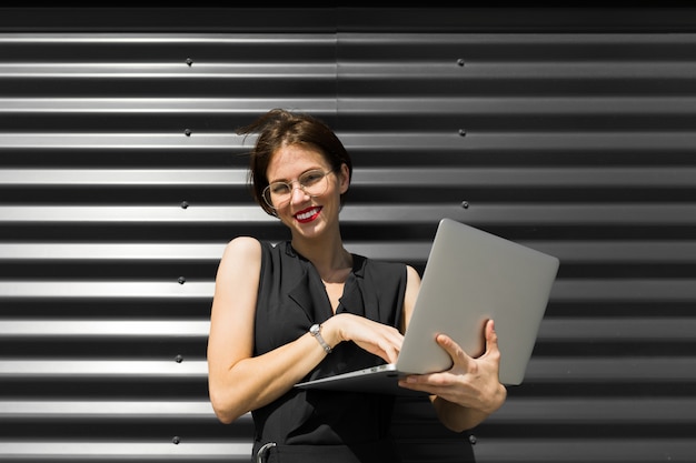 Caucasian woman in office clothes with laptop near the office building