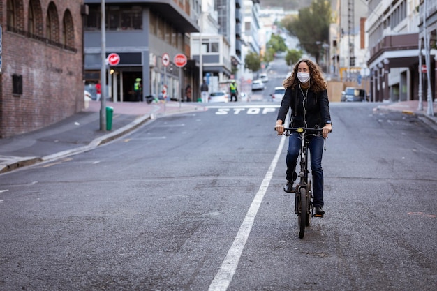 caucasian woman out and about in the city streets during the day, wearing a face mask against air pollution and covid19 coronavirus, cycling