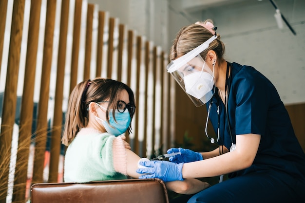 Caucasian woman patient getting vaccinated against coronavirus receiving covid vaccine. Intramuscular injection during doctor's appointment in hospital. Covid-19 Vaccination.