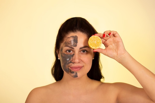 Caucasian woman portrait in 30 40 ages with clay face mask with\
lemon vitamin c