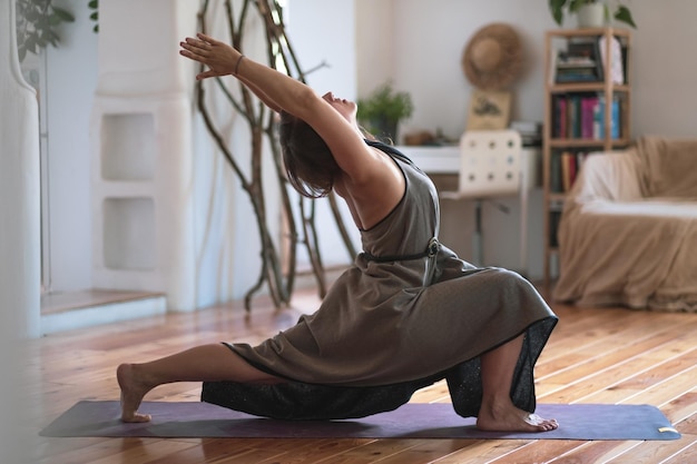 Donna caucasica che pratica yoga facendo variazione di posa del guerriero