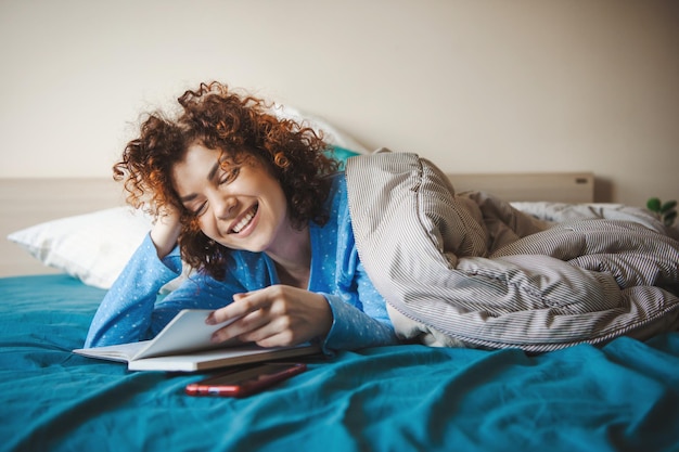 Donna caucasica che legge qualcosa durante il tempo libero in camera da letto faccia sorridente coronavirus