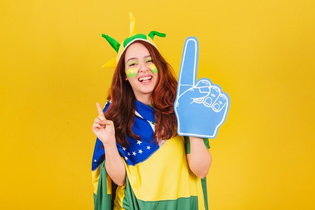 Photo caucasian woman redhead soccer fan from brazil using foam finger cheering coleographed dance