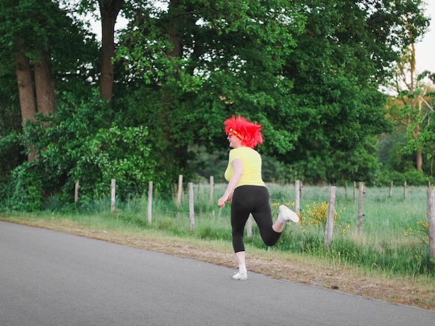 Caucasian woman runner in a belgian flag wig runs in a funny marathon